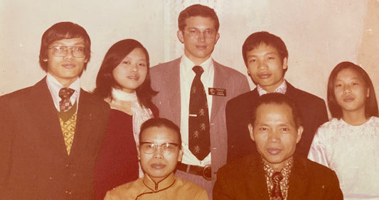 A family with two missionaries in formal attire posing for a photograph