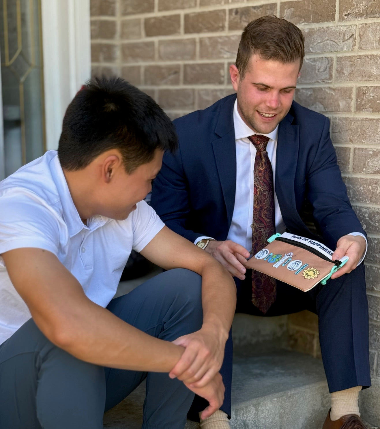 Two men sitting and looking at the All In Pouch