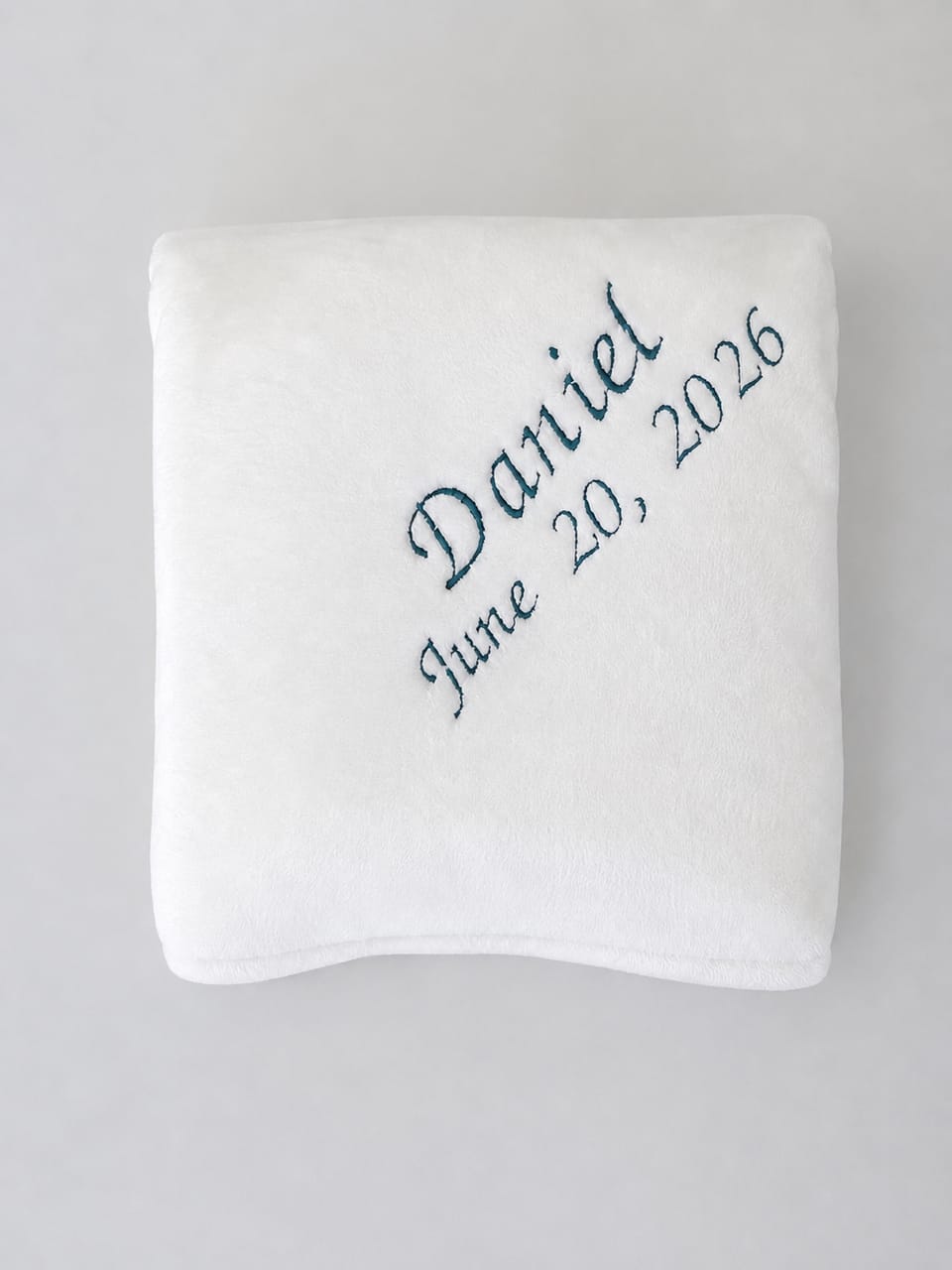 White blanket with the Name 'Daniel' and the date 'June 20, 2026' embroidered in royal blue thread