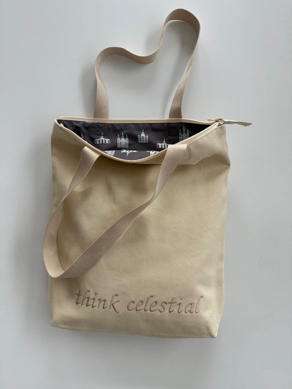 Canvas Ivory temple bag with tan strap and temples lining, embroidered with “think celestial”