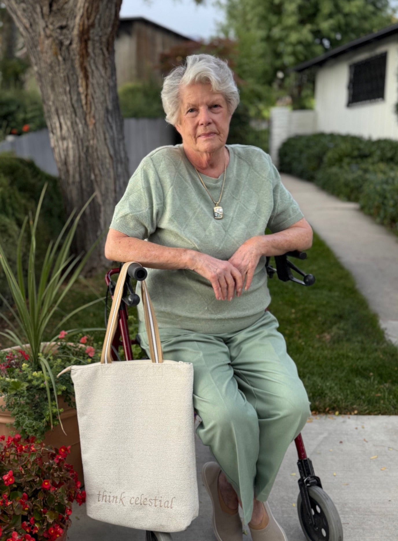 Senior woman sitting outdoors with an Upholstery Ivory temple bag hanging on one handle of a walker