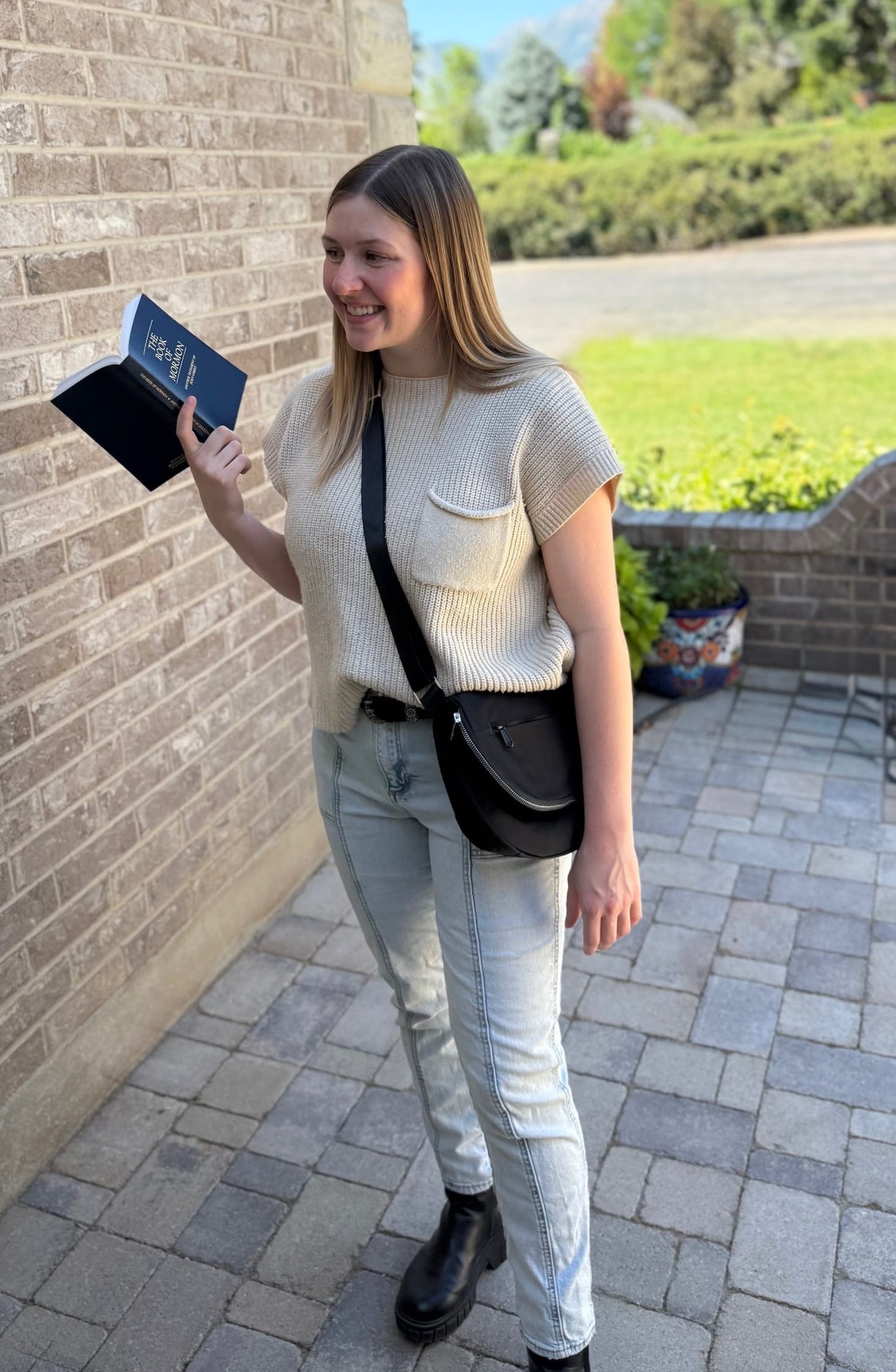Woman standing with Smiley Bag and holding a Book of Mormon