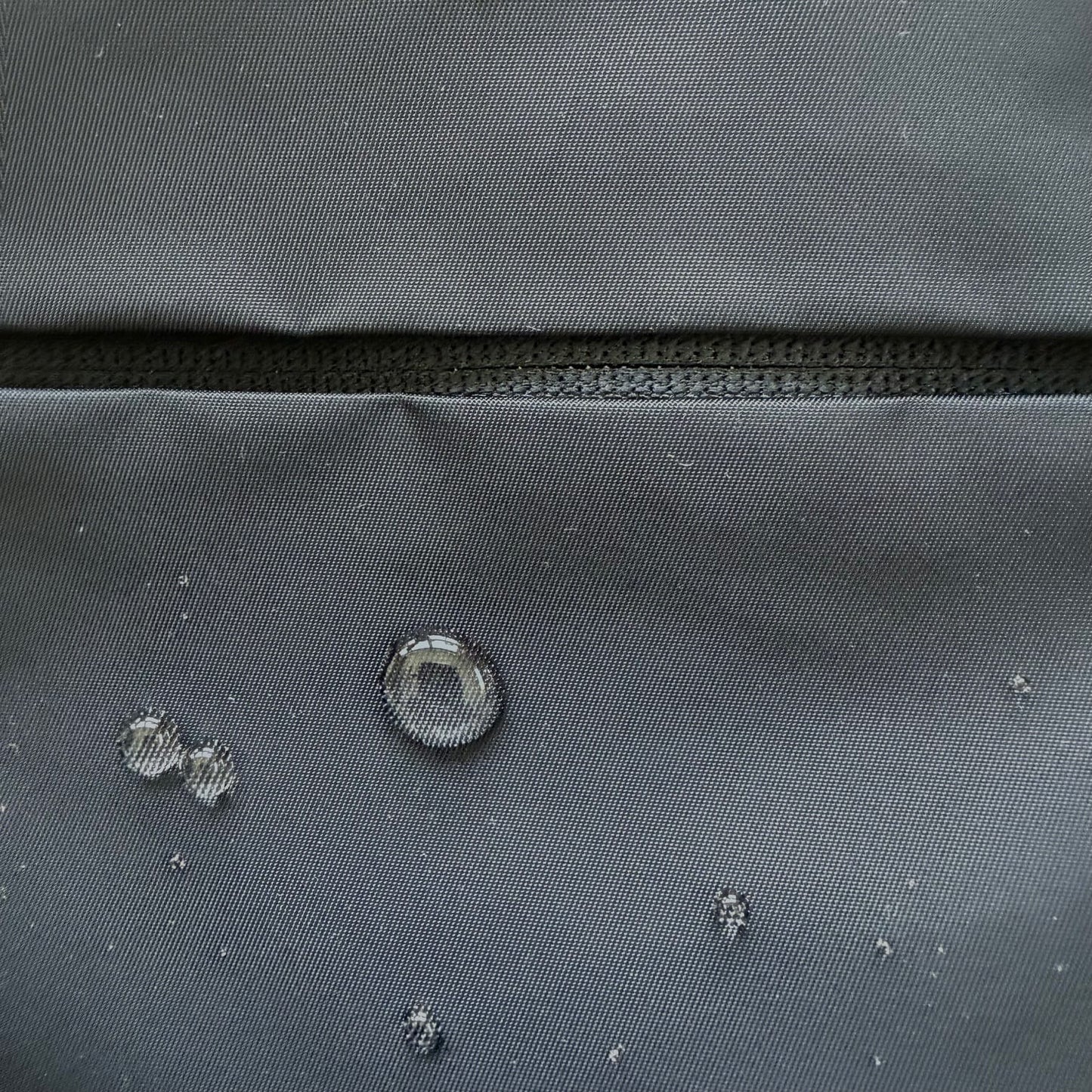 Close-up of canvas gray fabric with water droplets demonstrating water resistance.
