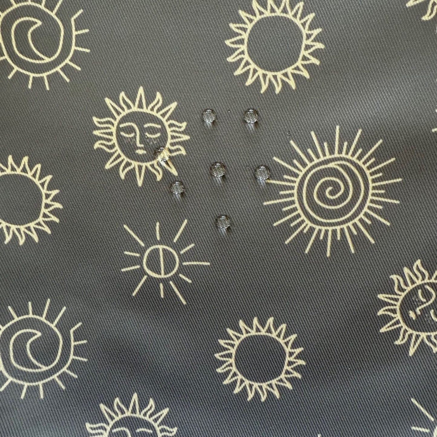Close-up of sunstones print fabric showing water droplets on the surface to demonstrate water resistance