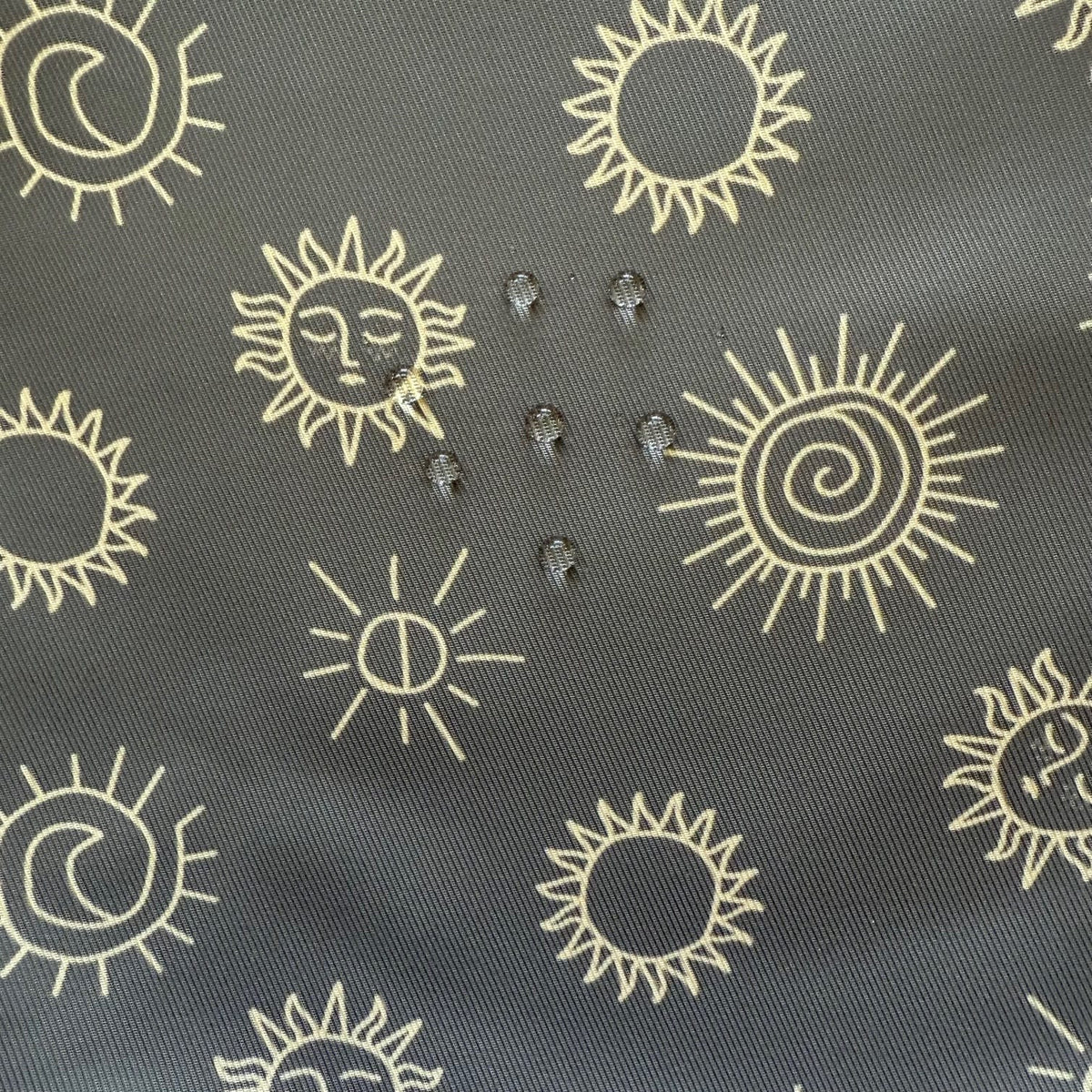 Close-up of sunstones print fabric showing water droplets on the surface to demonstrate water resistance