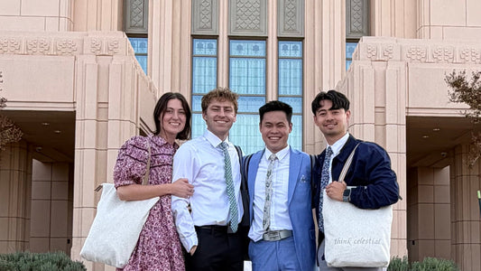 Four individuals posing in front of a The Church of Jesus Christ of Latter-day Saints temple. Two of the individuals are carrying ivory colored temple bags.