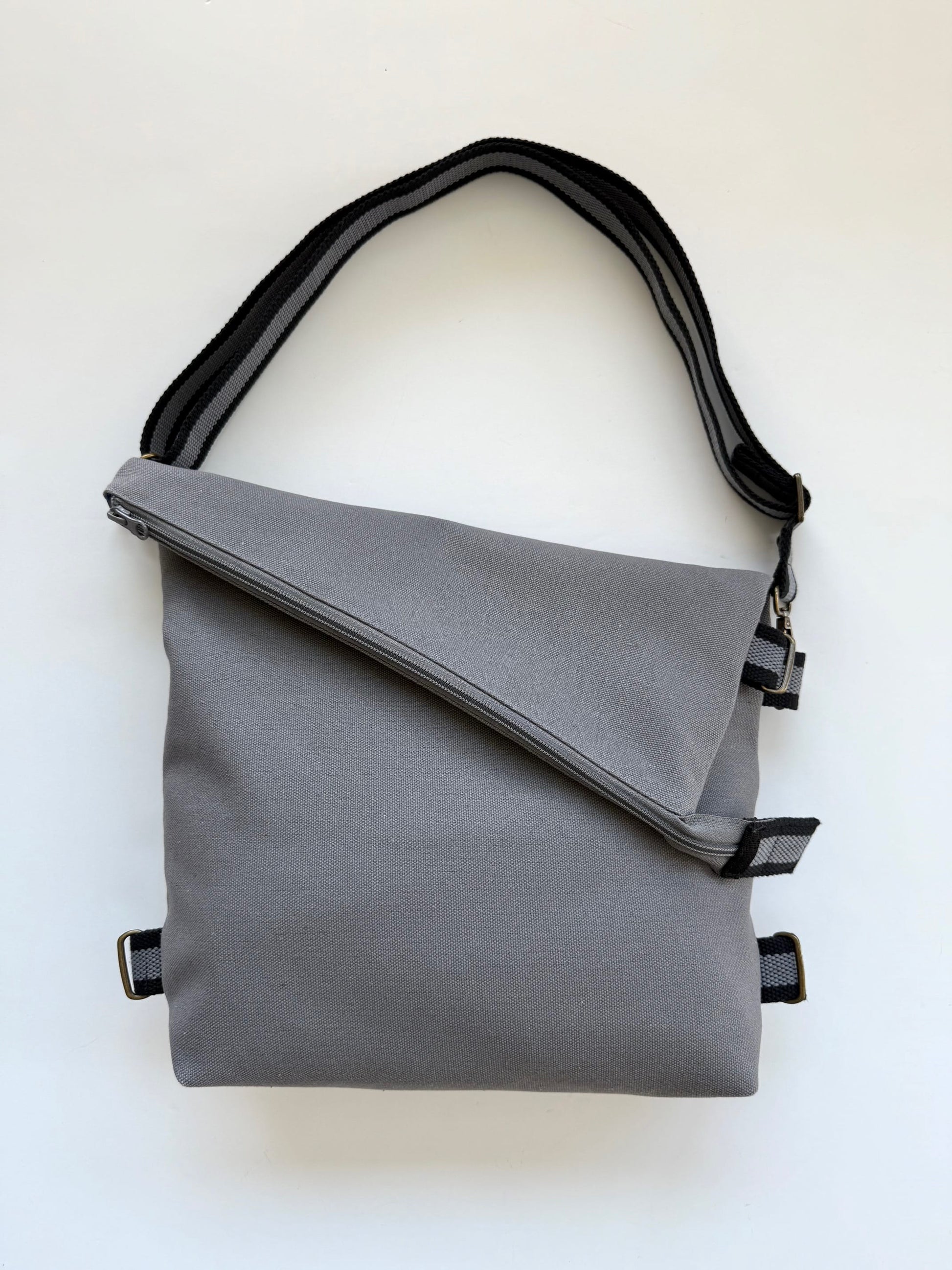 Canvas Gray 3-In-1 convertible missionary bag crossbody style with an adjustable black-and-gray strap.