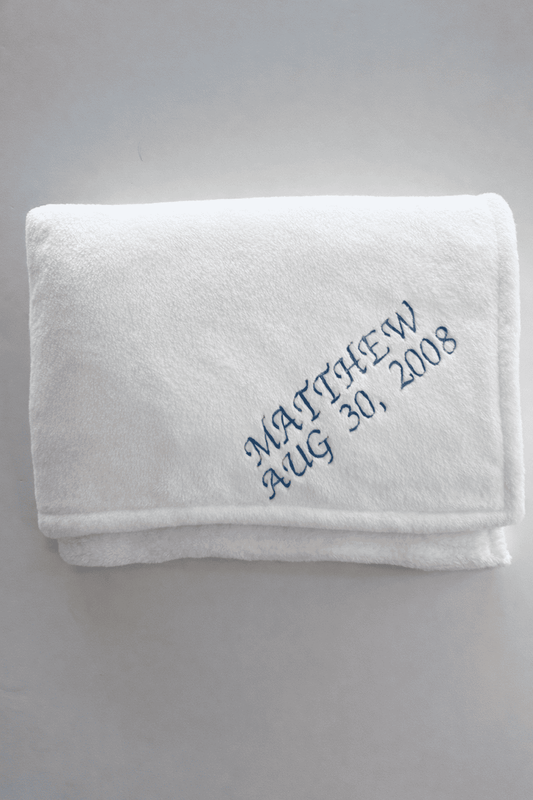 White blanket with the Name 'Matthew' and the date 'Aug 30, 2008' embroidered in royal blue thread