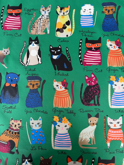 Pattern of colorful cats in various outfits on a green background