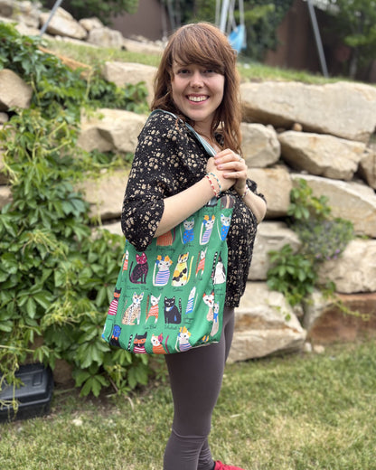 Woman carrying a green shoulder bag with a cat pattern outdoors