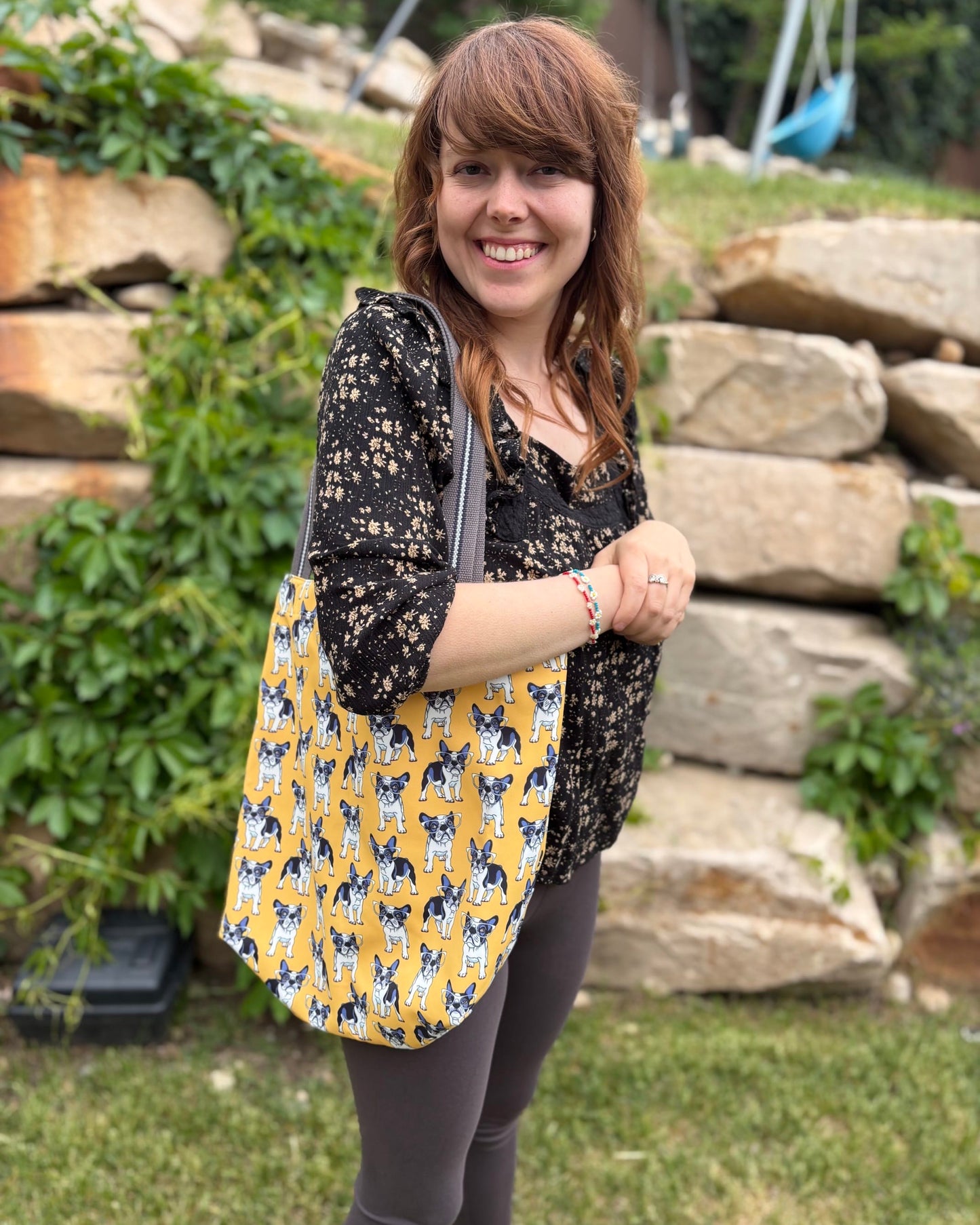 Woman carrying a yellow shoulder bag with a dog pattern outdoors