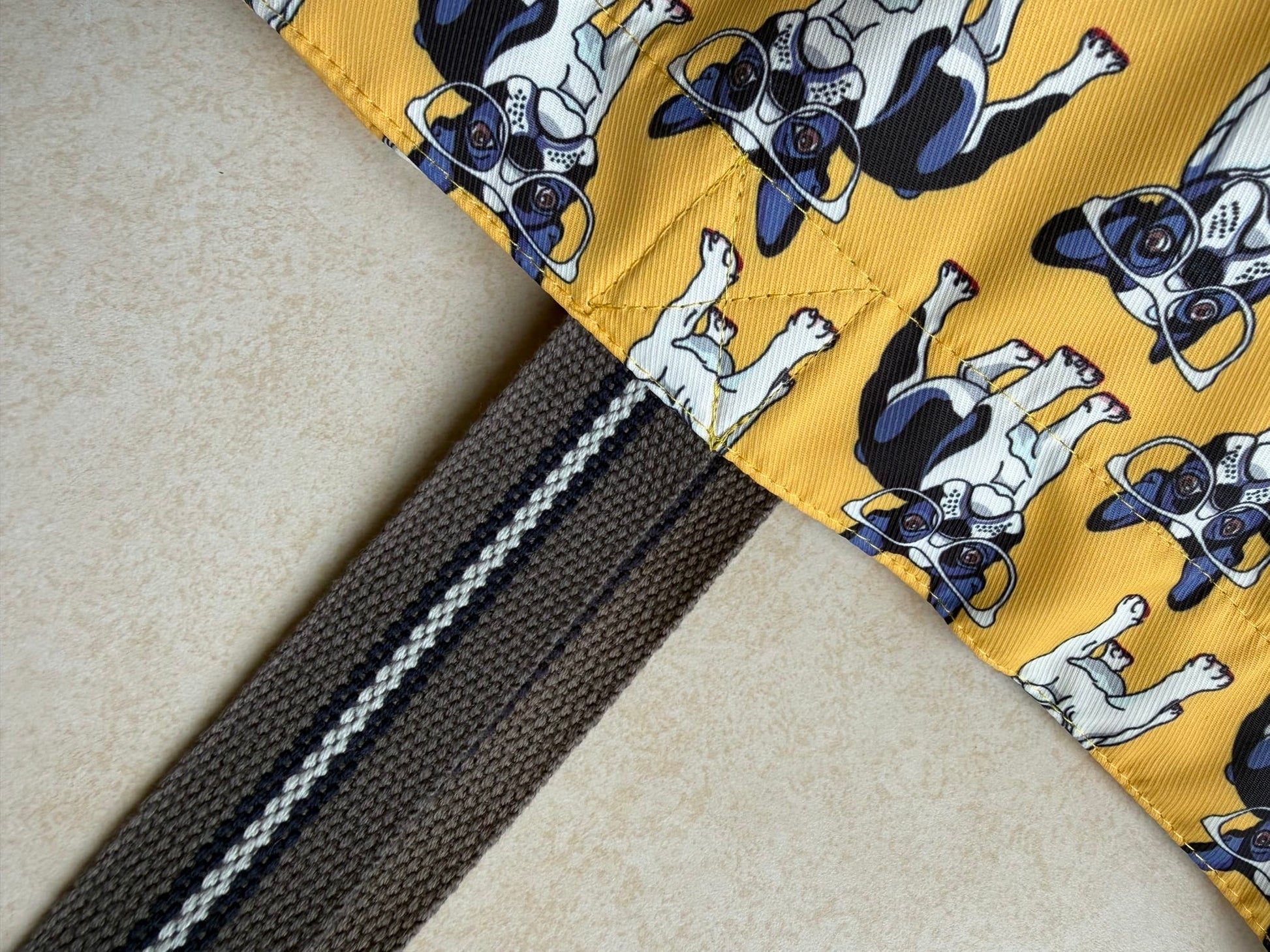 Fabric with dog pattern attached to dark brown straps 
