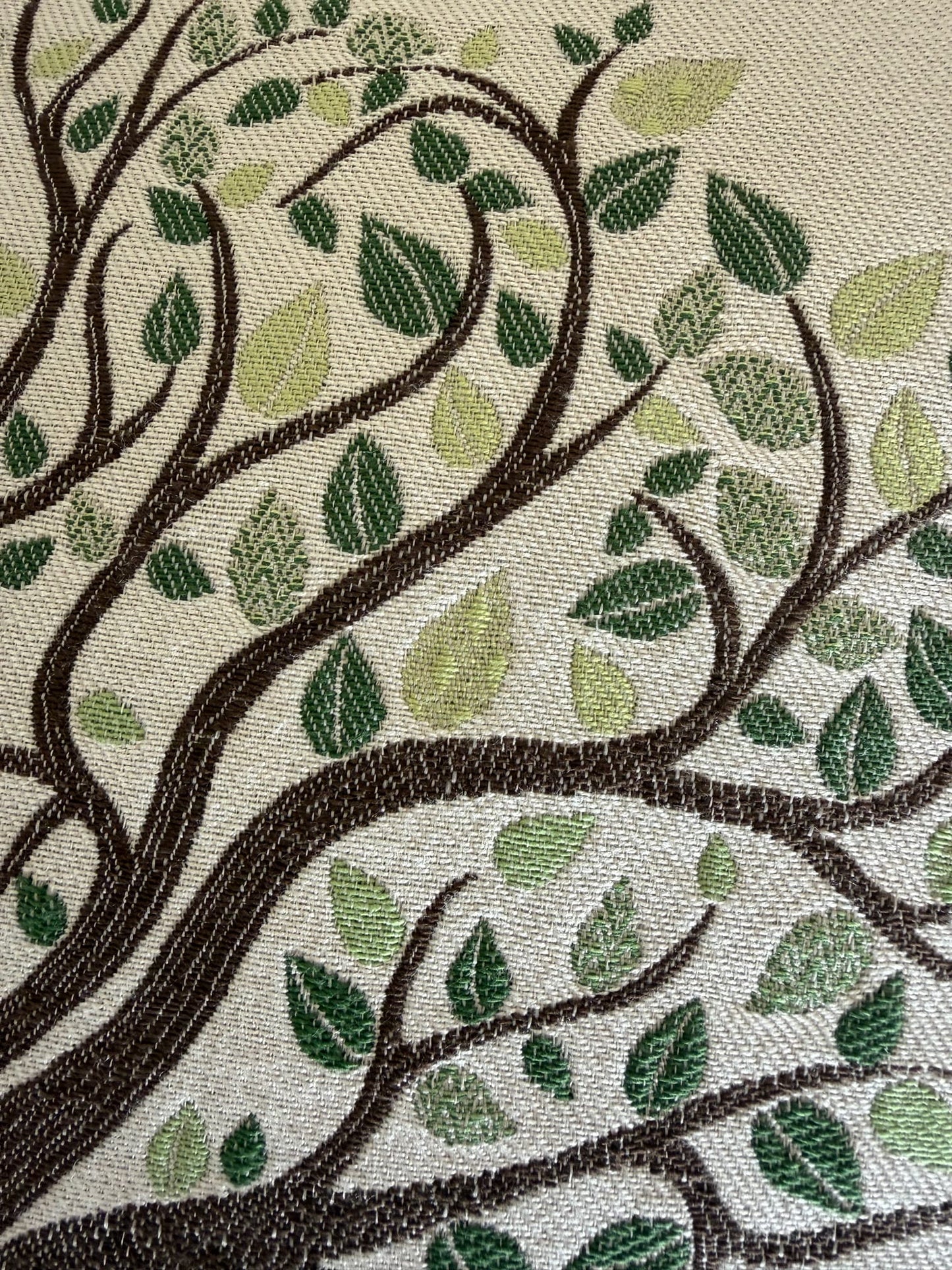 Detailed close-up of embroidered family tree design with woven texture featuring dark brown branches and green leaves
