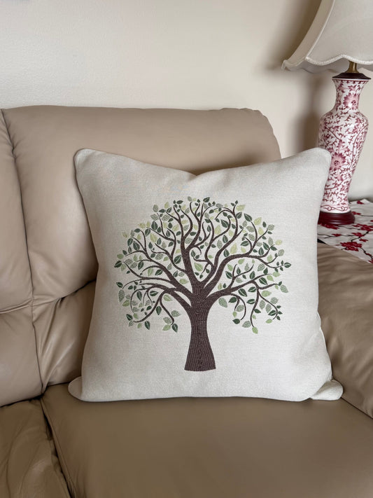 Family Tree decorative embroidered pillow on a beige couch.