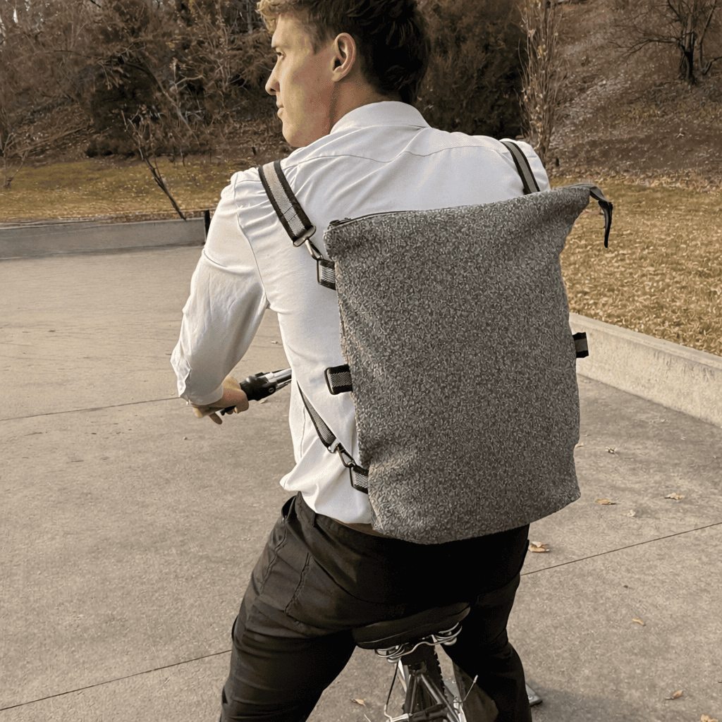 Man riding a bicycle with a gray backpack 
