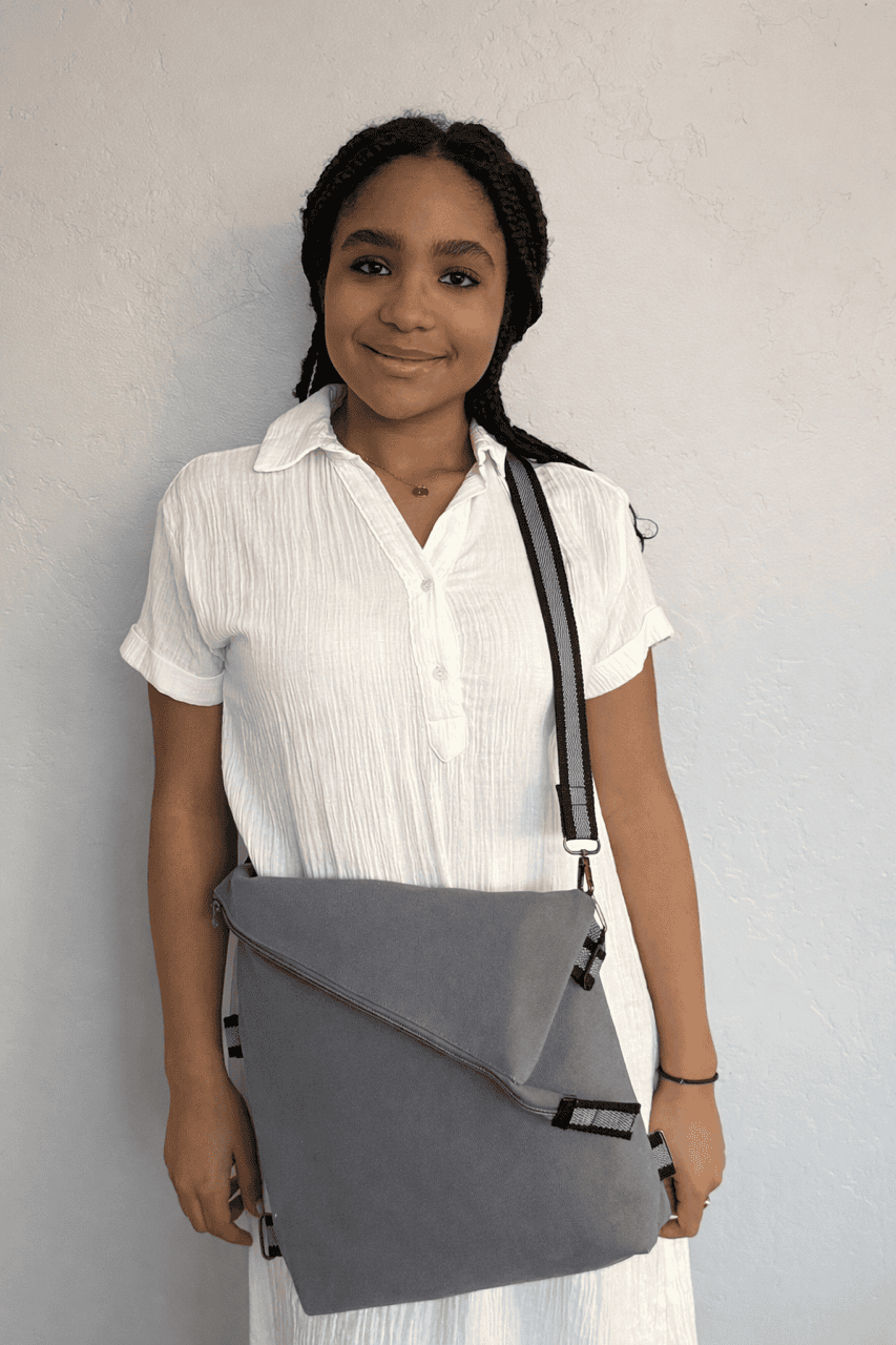 Girl wearing a white shirt carrying a gray crossbody shoulder bag