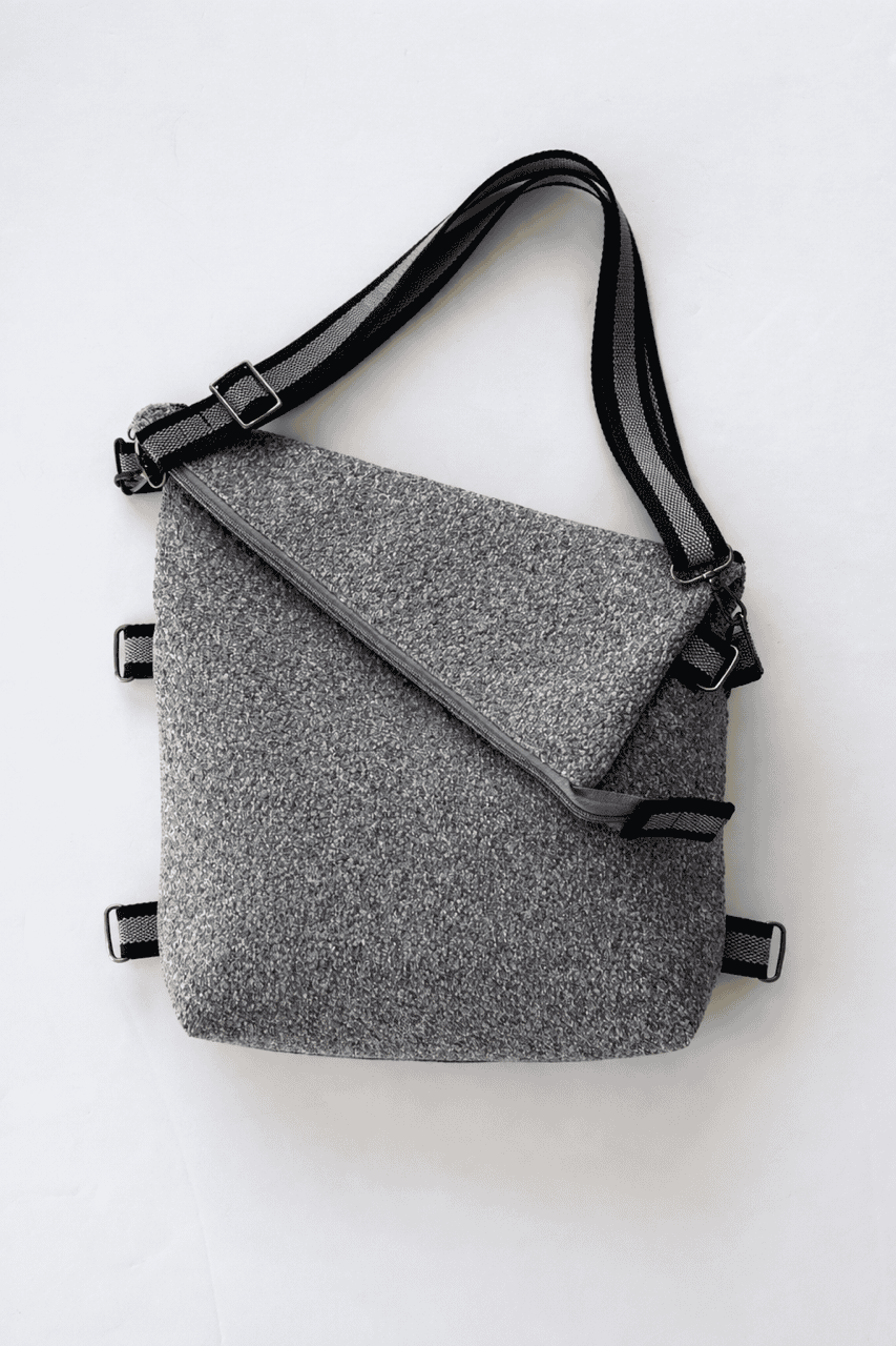 Gray crossbody shoulder bag with gray and black striped straps on a white background