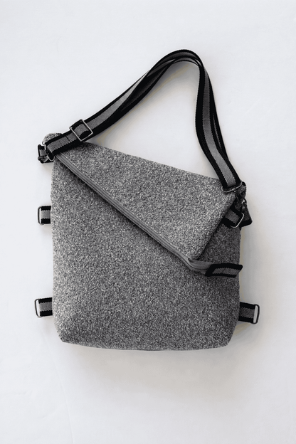 Gray crossbody shoulder bag with gray and black striped straps on a white background