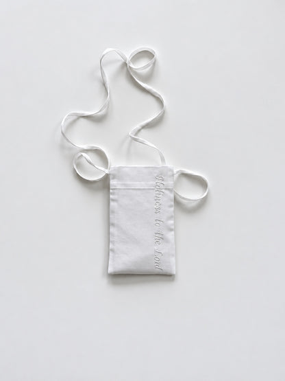 White cotton pouch with a lanyard and the phrase 'Holiness to the Lord' embroidered in white