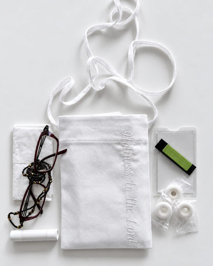 White cotton pouch with a lanyard displayed next to tissues, eyeglasses, lip balm, card holder, name badge, and breath mints