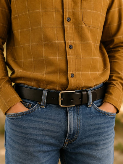 Person wearing a dark ochre plaid shirt and blue jeans with a black belt.