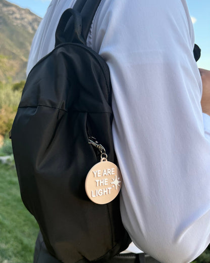 Black LDS Mission Ready Convertible Bag worn over one shoulder against the back, with a “Ye Are the Light” charm