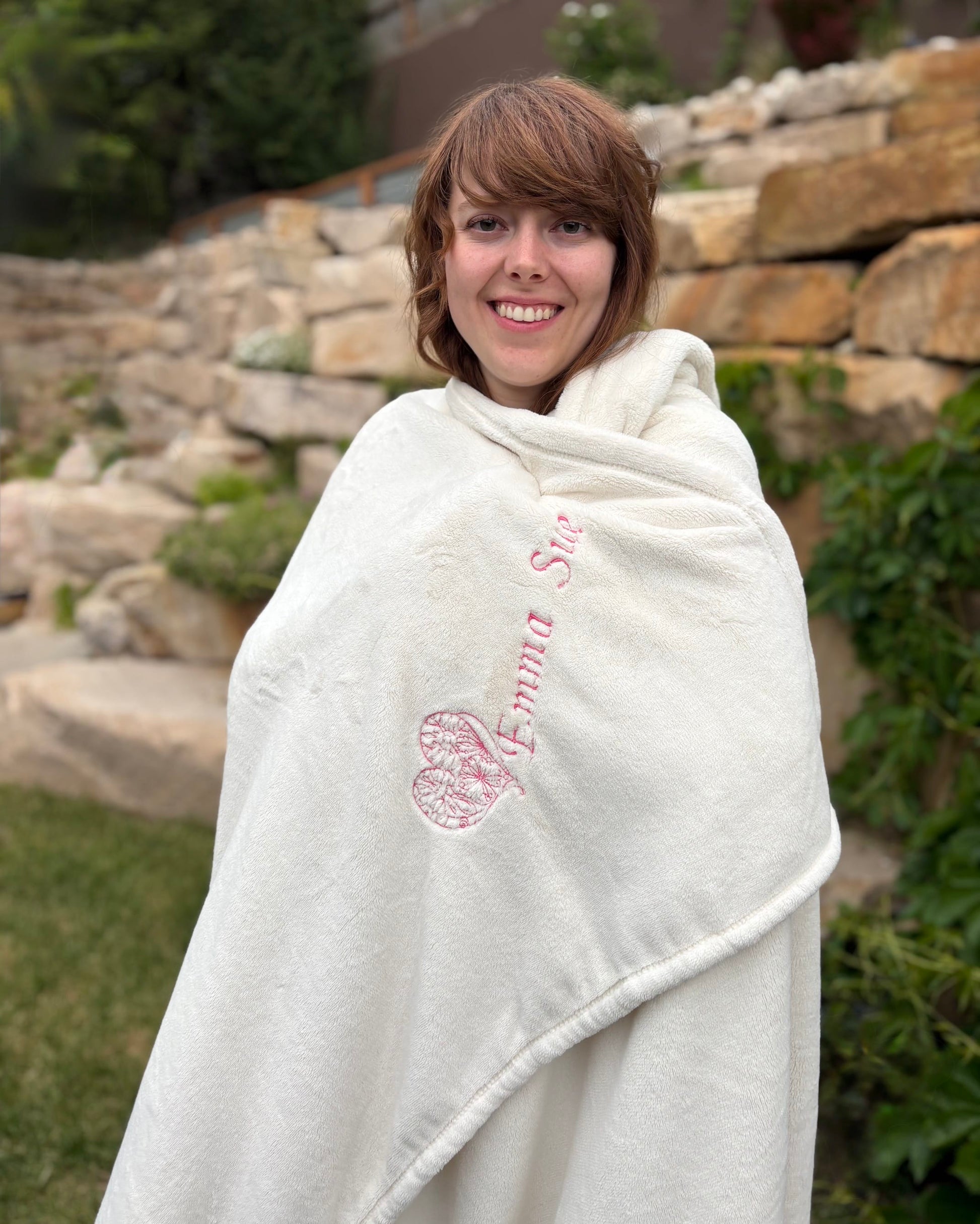 Woman wrapped in a white blanket with pink text outdoors