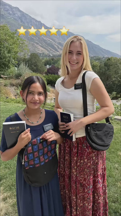 Two sister missionaries display black missionary bags outdoors, one open to reveal its colorful lining