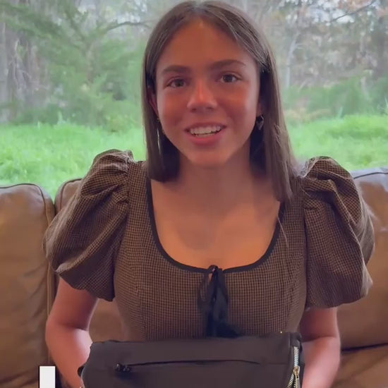 A young woman shows the various pockets and interior of a woman's crossbody bag purse.