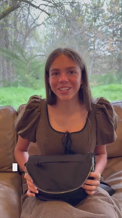 A young woman shows the various pockets and interior of a woman's crossbody bag purse.